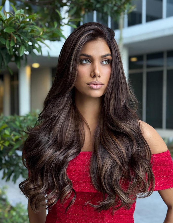 Young woman with long wavy hair wearing a red off-shoulder dress, representing Miss Universe Cuba nepo baby controversy.