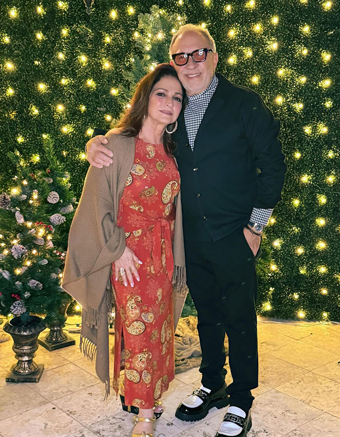 Couple posing by a lit festive backdrop with Christmas trees, symbolizing after Nepo Baby wins Miss Universe Cuba.