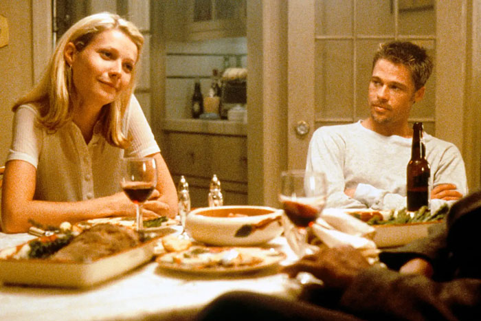 Gwyneth Paltrow and Brad Pitt seated at a dinner table with wine, sharing a quiet moment during their relationship.