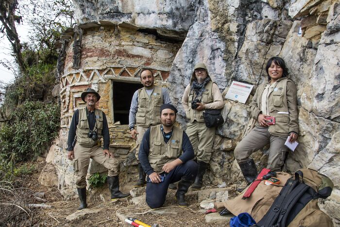 Archaeologists in gear posing near ancient stone structures linked to mysterious ancient civilization excavation site. - 12