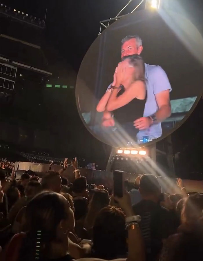 Astronomer CEO Andy Byron caught on kiss cam at Coldplay show, crowd reacting in stadium with large screen display.