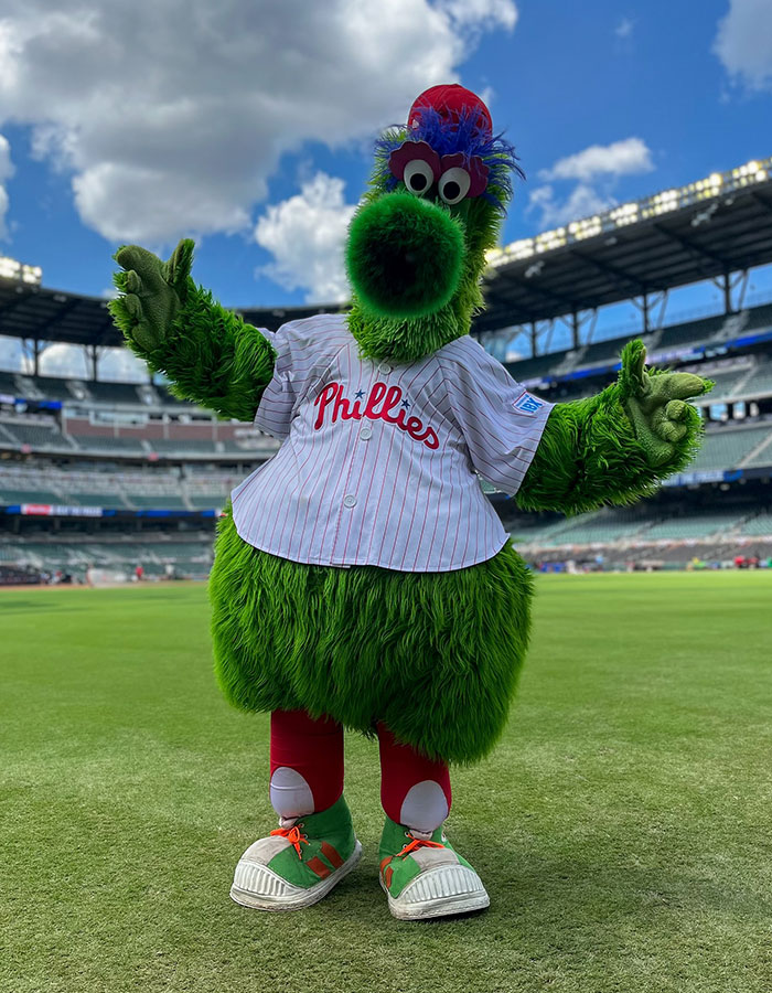 Philadelphia Phillies mascot on field, humorously mocking CEO during baseball kiss cam scandal event.