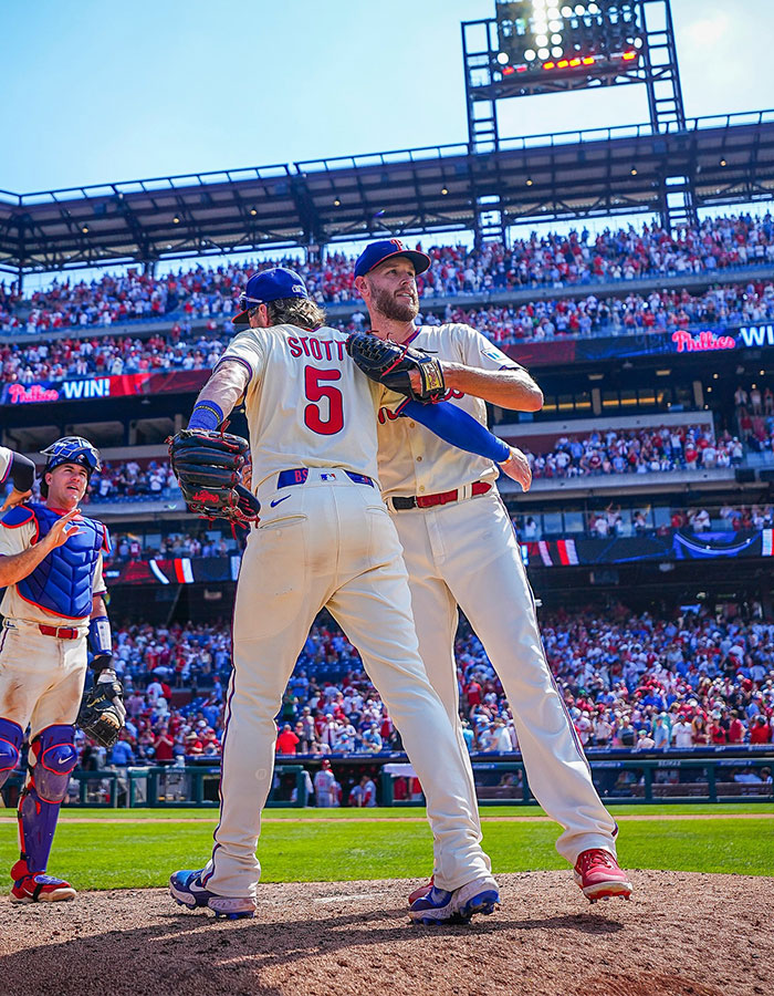 Baseball players celebrating on field with cheering crowd in background during a lively game moment at the stadium.