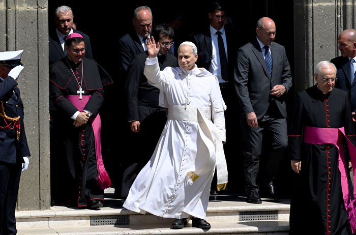 Doctor involved in Pope Leo’s miracle waving while surrounded by clergy and security outside a historic building. - 8