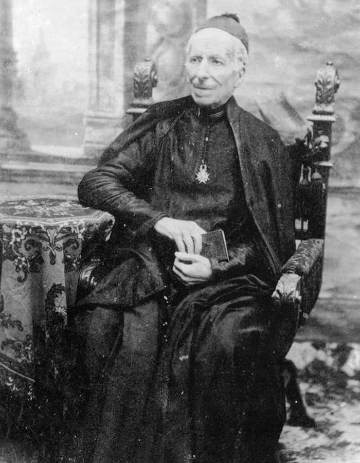 Old black and white photo of a doctor involved in Pope Leo’s miracle sitting in a chair with religious attire. - 5