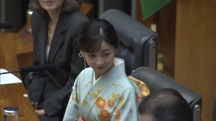Japanese Princess Kako wearing traditional kimono, looking down while attending a formal event with others in the background