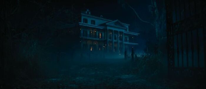 Dark eerie mansion at night with fog and bare trees, perfect for a worst movie tropes quiz setting in horror films.