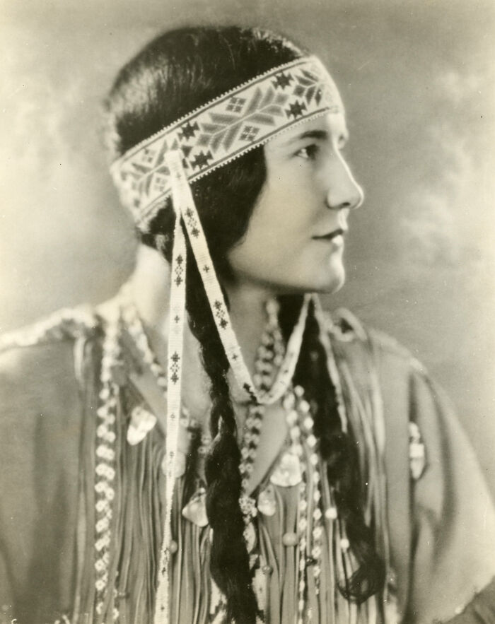 Vintage portrait of a woman with braids and a patterned headband, showcasing timeless beauty in a century-old photo.