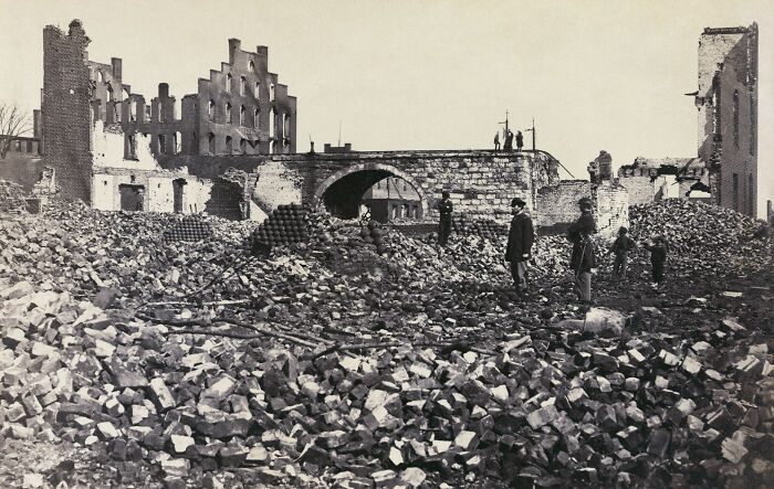 Black and white photo of people standing among rubble and ruins showing the real story of 1800s America.