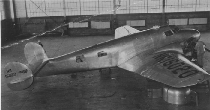 Vintage black and white photo of Amelia Earhart&rsquo;s airplane inside a hangar, linked to mystery and satellite clues discovery.