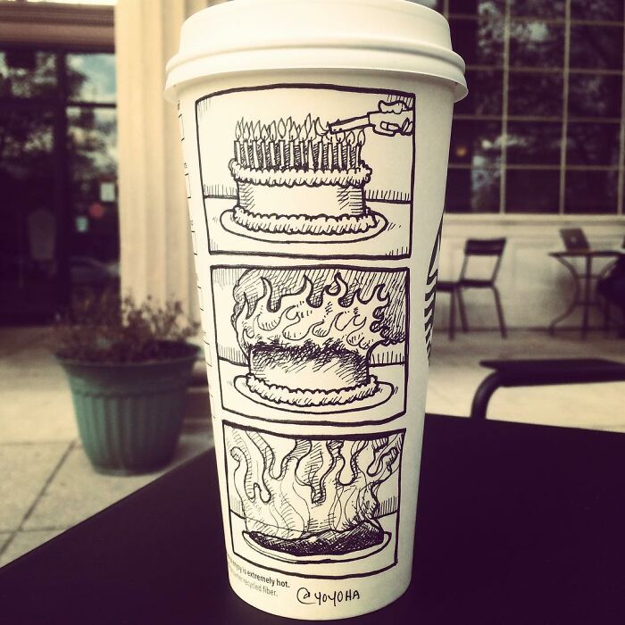 Coffee cup with a humorous cartoon showing a cake set on fire in three comic panels outside a cafe.