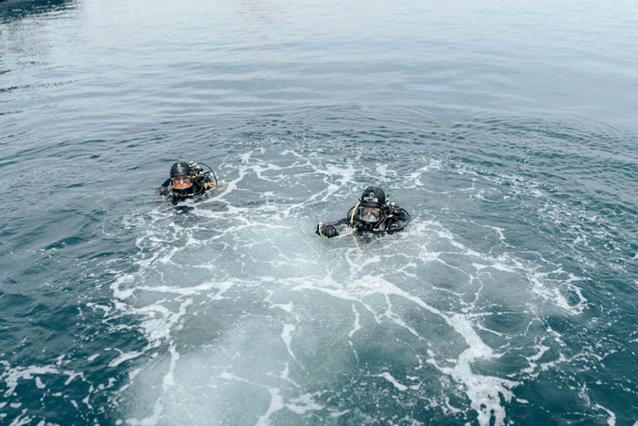 Two scuba divers in full gear floating on the ocean surface after dropping cow 1629 meters deep into sea for study