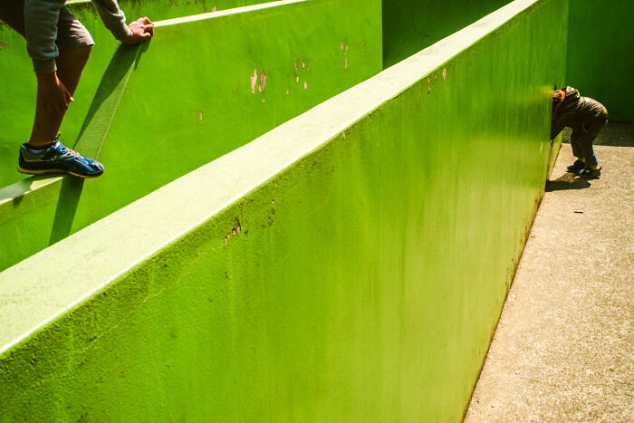 Children playing on bright green walls in an urban setting, capturing daily life in Japan through vibrant photography.