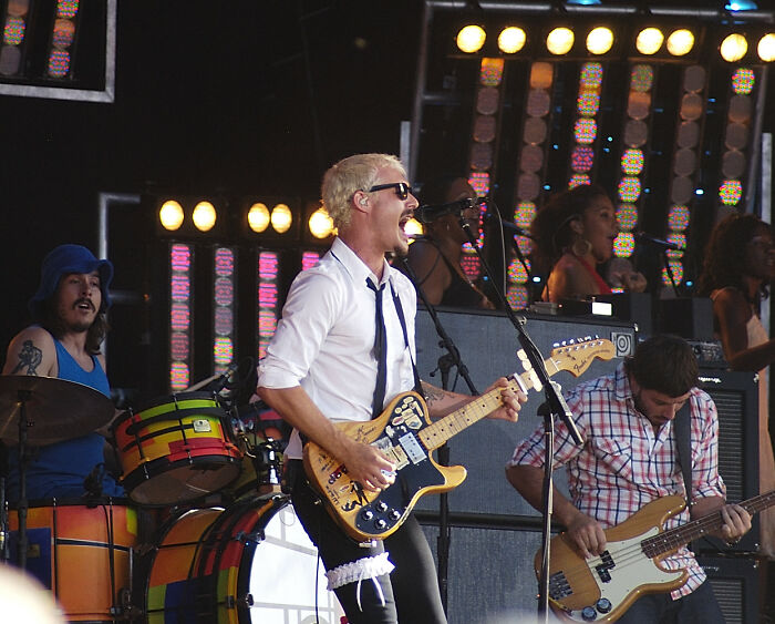 Band performing live on stage with energetic lead singer playing guitar, highlighting misunderstood celebrities in music.