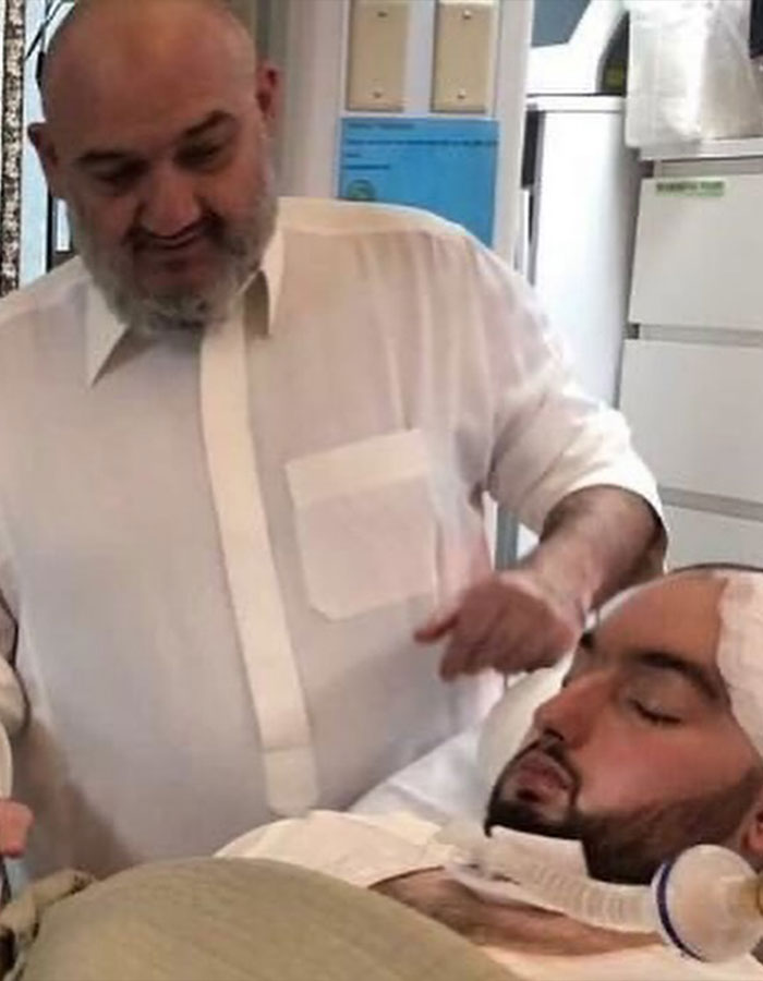 Man wearing a white shirt standing next to a bed with the Sleeping Prince of Saudi Arabia in a coma. Man wearing a white shirt standing next to a bed with the Sleeping Prince of Saudi Arabia in a coma.