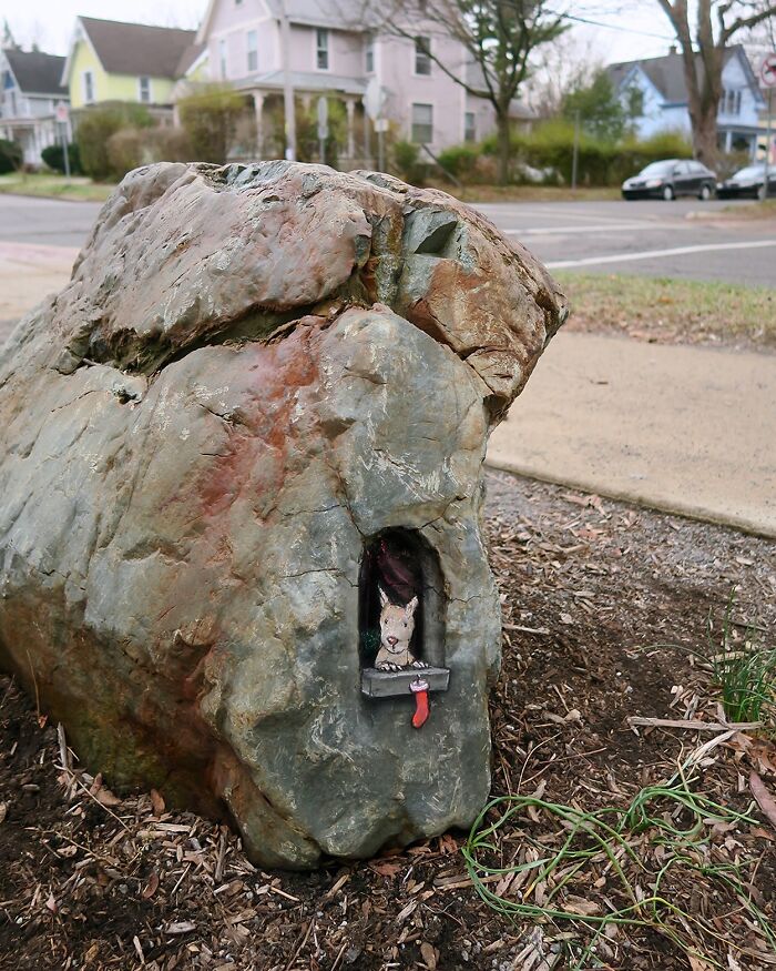 Sculpted rock with a small chalk-drawn dog in a window, showcasing David Zinn sidewalk chalk magical worlds art.