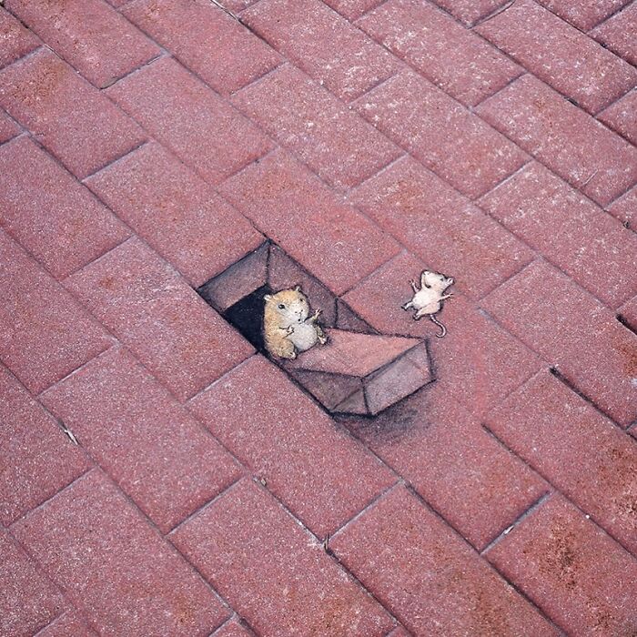 Chalk art by David Zinn showing a mouse popping out of a brick sidewalk hole in a magical chalk drawing.