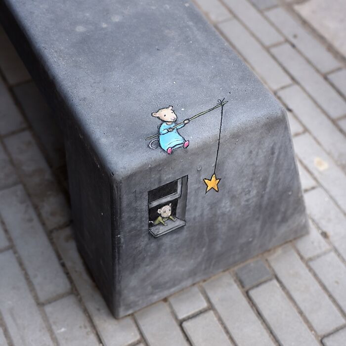 Chalk drawing by David Zinn of a mouse fishing for a star on a gray concrete block on a sidewalk.