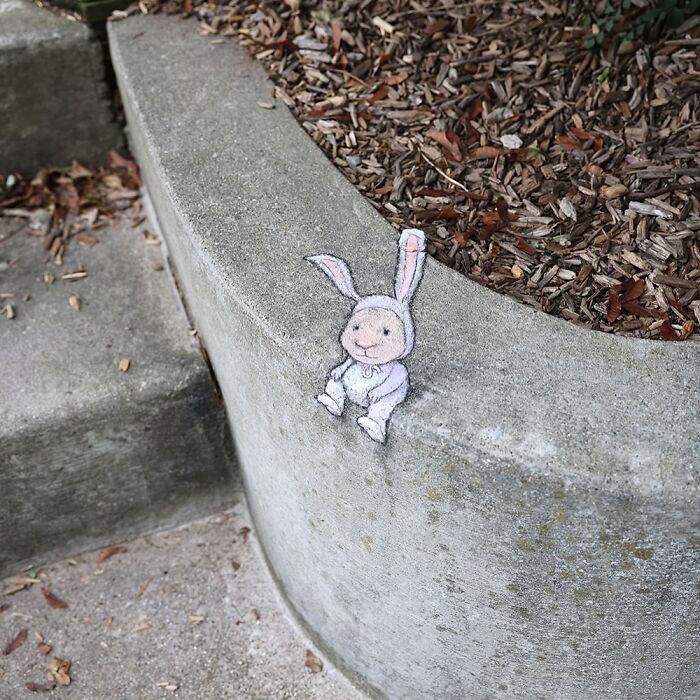 Chalk drawing by David Zinn of a small bunny sitting on a concrete ledge, showcasing magical sidewalk art.