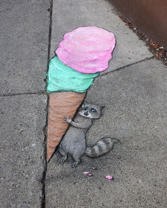 Chalk art by David Zinn on sidewalk shows a raccoon holding a large, colorful ice cream cone in a magical world.