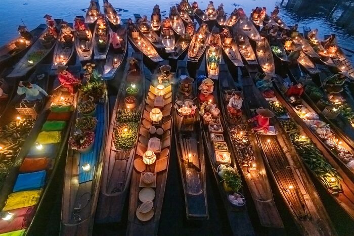 Floating market at dusk with vendors selling goods on boats, capturing the soul of Asia in a stunning photo.