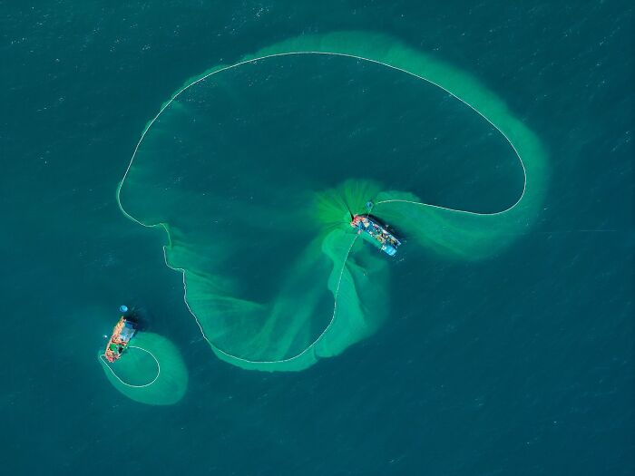 Aerial view of two fishing boats casting nets in the ocean, capturing the soul of Asia through stunning photos.