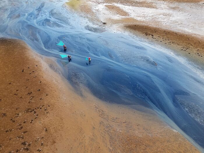 Aerial view of fishermen in shallow water blending brown earth and blue streams capturing the soul of Asia.