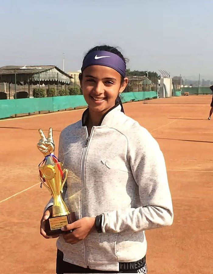 Young female tennis pro smiling on clay court holding a trophy, highlighting male ego controversy in sports. Young female tennis pro smiling on clay court holding a trophy, highlighting male ego controversy in sports.