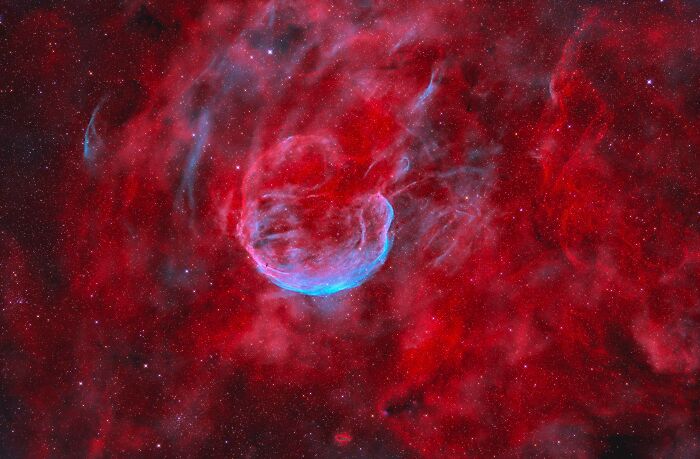 Vivid space photo showcasing a red nebula with a glowing blue center from the 2025 astronomy photographer shortlist.