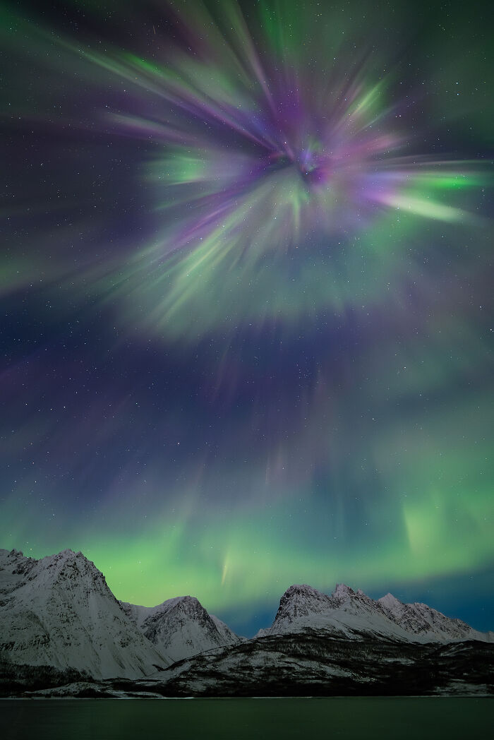 Aurora borealis in vibrant green and purple hues over snowy mountains in a breathtaking space photo from astronomy photography.