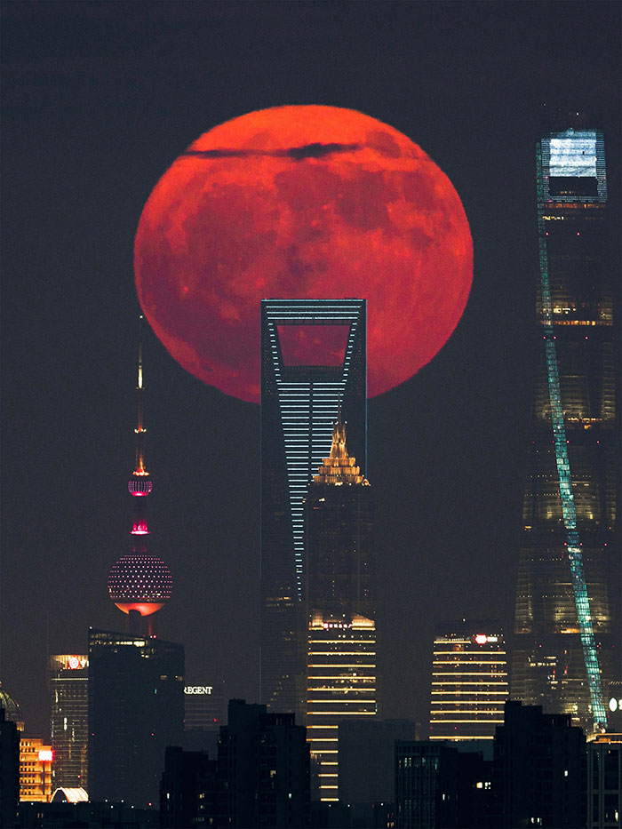 Massive red moon rising behind city skyscrapers captured in breathtaking space photo from astronomy photographer shortlist.