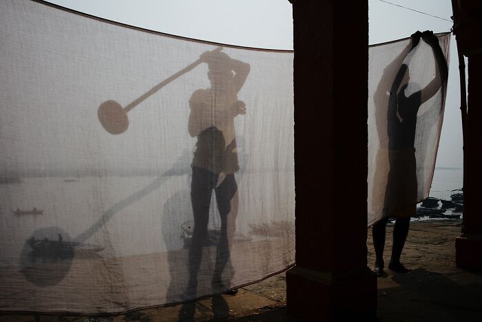 Silhouettes of people behind a cloth in a street photo capturing the soul of India by photographer Rohit Vohra.