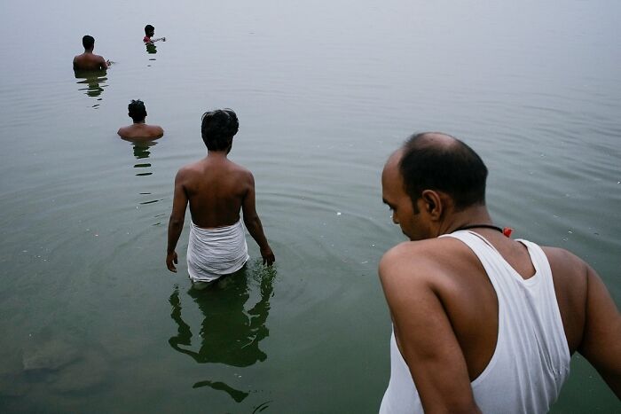 Men bathing in a river, captured in a powerful street photo reflecting the soul of India by photographer Rohit Vohra.