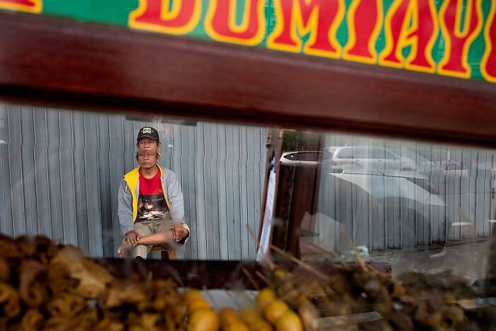 Man sitting inside a stall with street food, captured in a powerful street photo showcasing the soul of India.