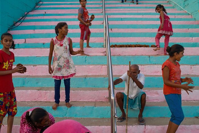 Children and an elderly man on colorful street stairs, a powerful street photo capturing the soul of India.
