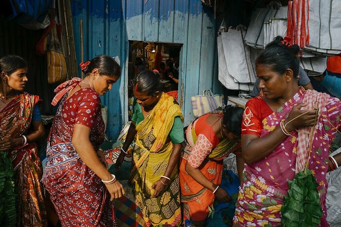 Women wearing colorful saris interacting at a vibrant street market in India, showcasing powerful street photos capturing the soul.
