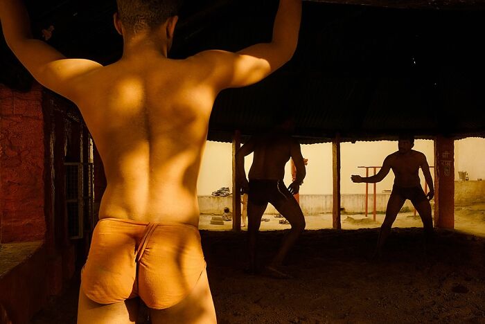 Young men practicing traditional wrestling in an Indian village, showcasing powerful street photos capturing the soul of India.