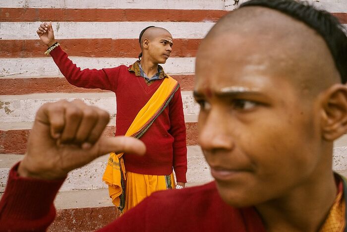 Two young men with traditional attire in a vibrant street scene, showcasing powerful street photos capturing the soul of India.