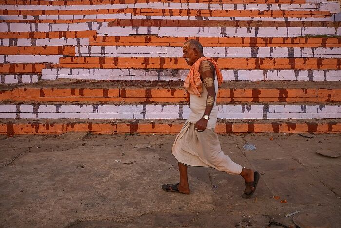 Elderly man walking past a colorful wall in a street photo capturing the soul of India by Rohit Vohra.