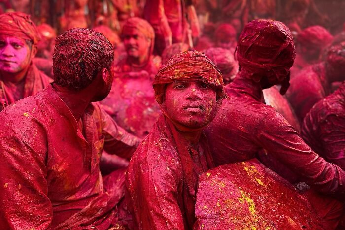 Men covered in vibrant red and yellow powder during a street festival, showcasing powerful street photos capturing the soul of India.