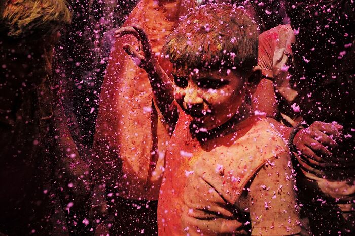 Child covered in vibrant pink powder during a lively street festival, capturing the soul of India in a powerful moment.