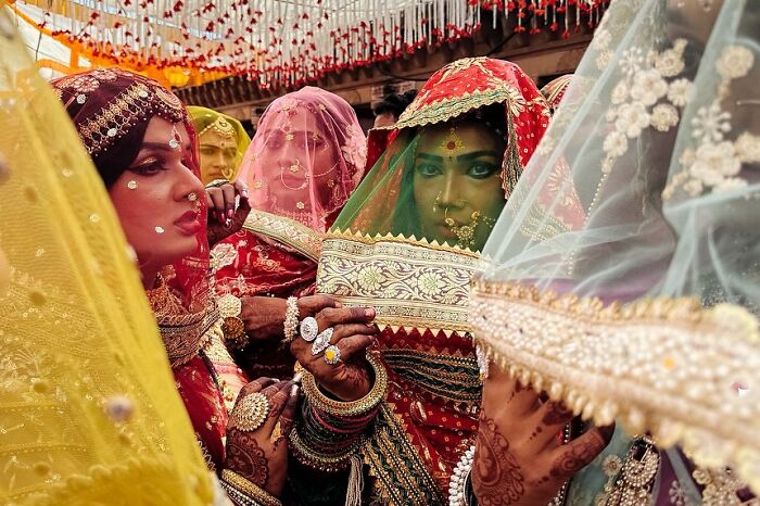 Indian women in traditional colorful bridal attire with intricate jewelry at a vibrant street celebration, capturing powerful street photos.