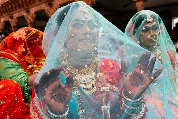 Traditional Indian women in vibrant attire with henna on hands and jewelry, captured in powerful street photos of India.