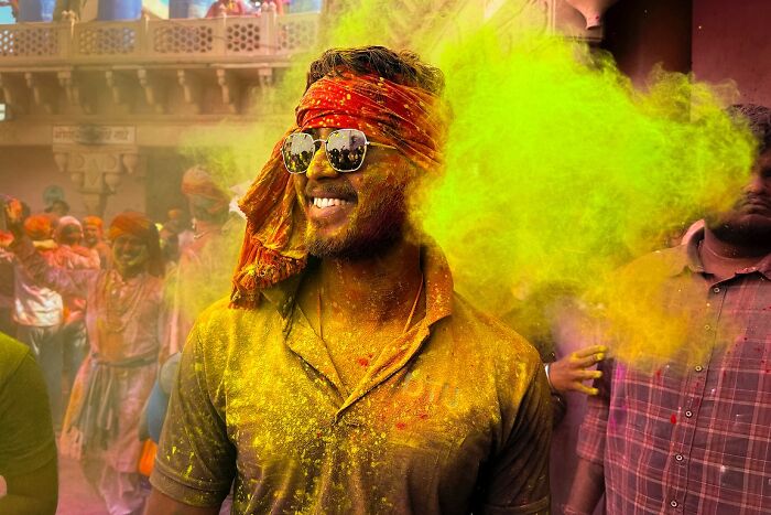 Man covered in vibrant yellow powder during a colorful street photo capturing the soul of India festival celebration.