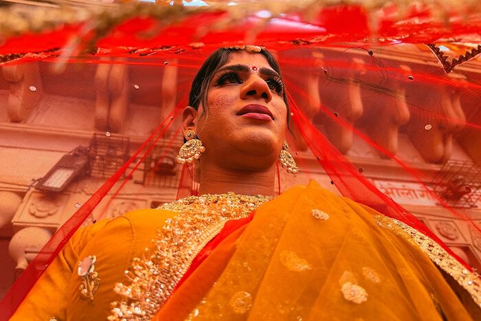 Vibrant street photo capturing an Indian woman in traditional attire with intricate jewelry and a red veil.