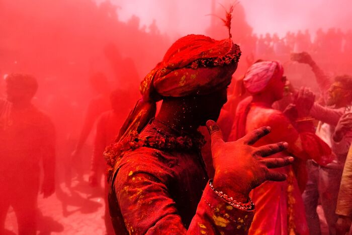 Man covered in red powder celebrating Holi festival in vibrant street photo capturing the soul of India by Rohit Vohra.