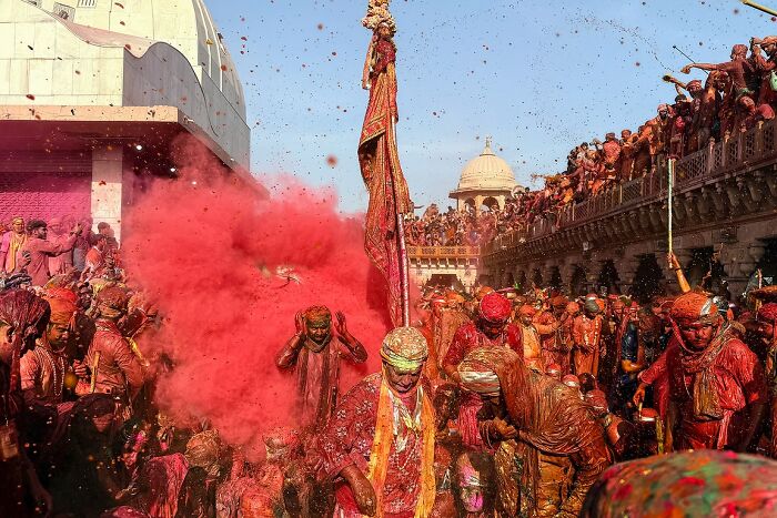 Crowd celebrating Holi festival covered in vibrant colored powders in a powerful street photo capturing the soul of India.