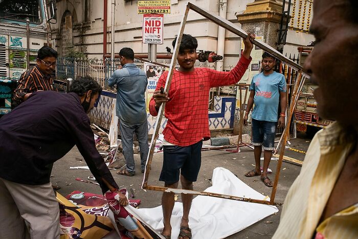 Men working on a busy street in India, framed through a wooden rectangle in a powerful street photo capturing India's soul.