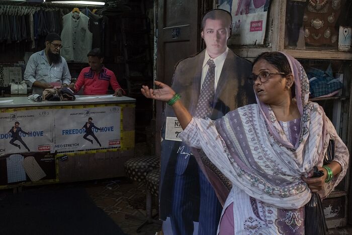 Woman in traditional attire gesturing in a busy market, a powerful street photo capturing the soul of India.