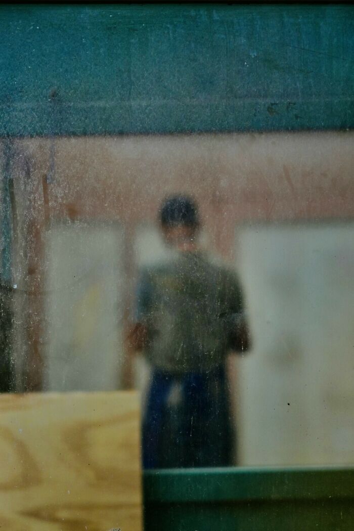 Blurred color photograph of a person seen through a dirty glass window, showcasing unique color photography style.